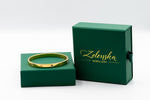 Gold bracelet on a green box with 'Zelenska Jewellery' branding.