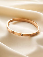 Rose gold bracelet with diamond accents on a beige fabric background