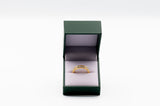 Gold ring in a green jewelry box on a white background