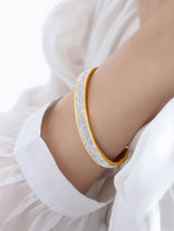 Gold bracelet with clear stones on a person's wrist against a white background
