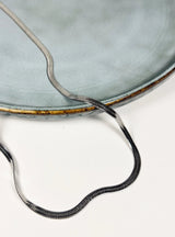 Necklace with a textured chain on a light gray background