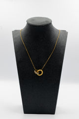 Gold necklace with a heart-shaped pendant on a black mannequin bust against a white background