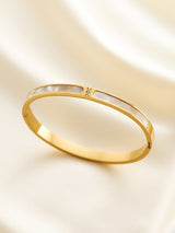 Gold bracelet with a diamond on a light beige background