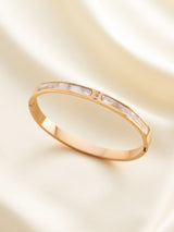 Gold bracelet with a subtle design on a beige background