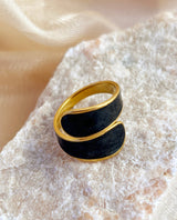 Gold and black ring on a textured beige surface