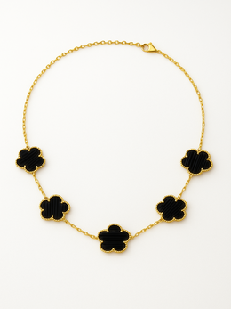 Gold necklace with black flower-shaped pendants on a white background